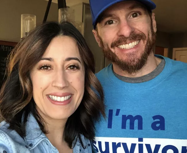 A man and a woman smile, as the man is a colorectal cancer survivor.